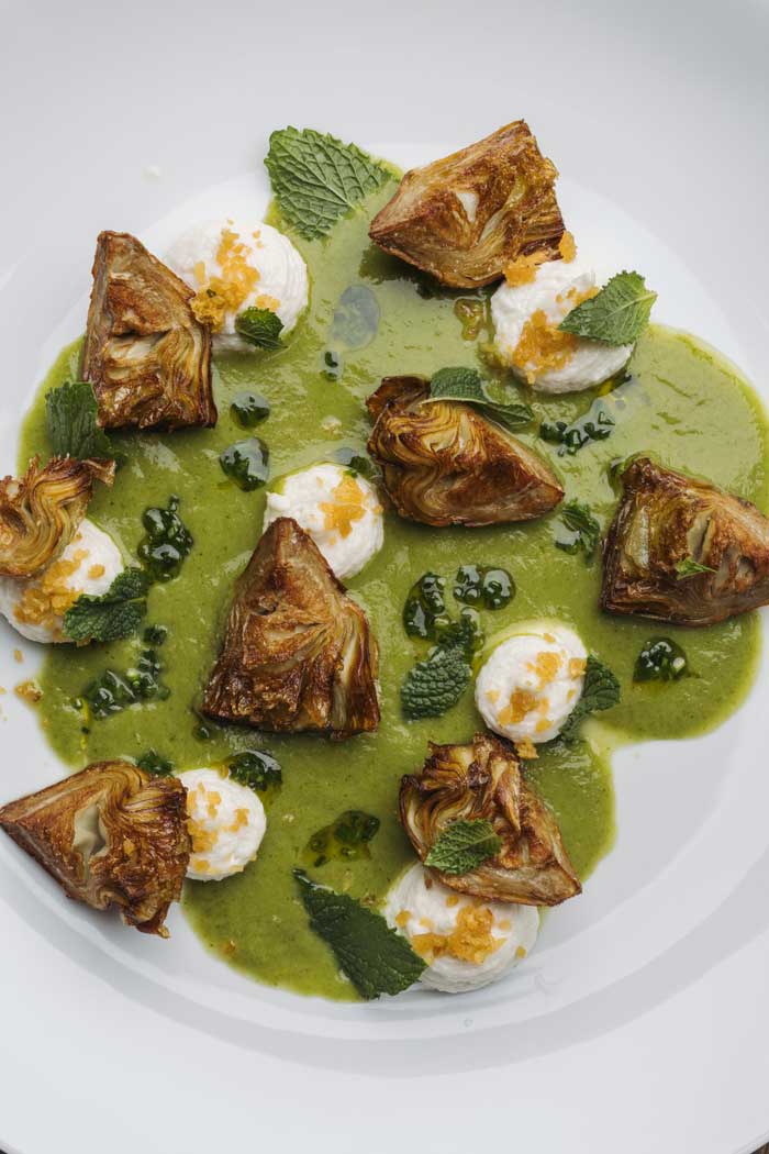 Alcachofas crujientes con bacalao sobre curry de hierbas frescas, plato servido en Kulto Madrid Retiro