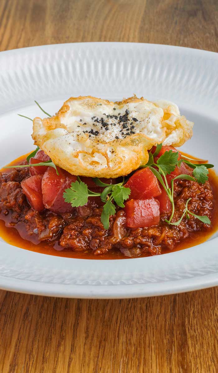 Plato de atún aliñado con huevo y tomate frito casero servido en el restaurante Kulto en Madrid Retiro