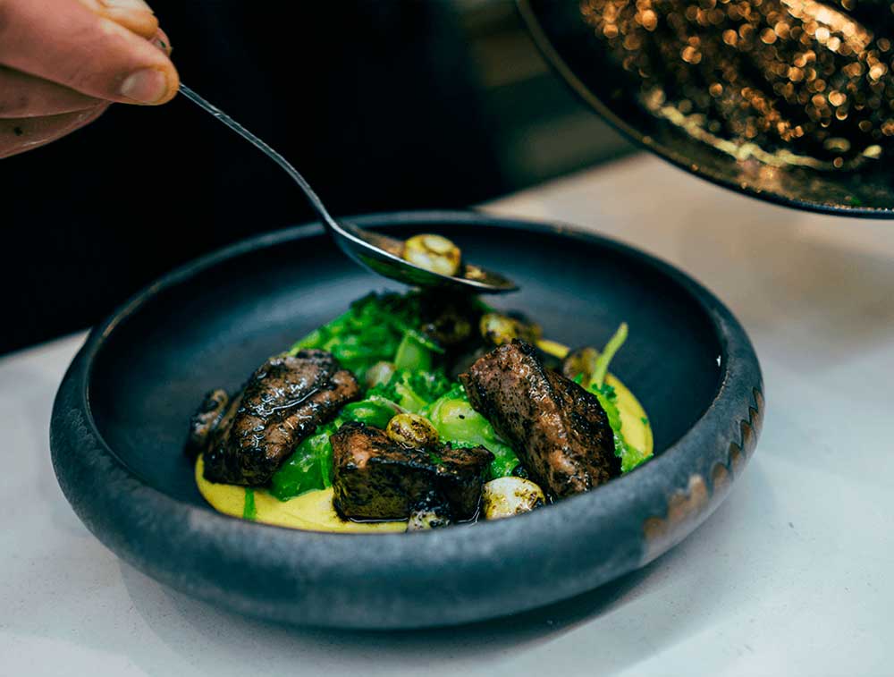 El chef José Fuentes decorando platos con hierbas frescas