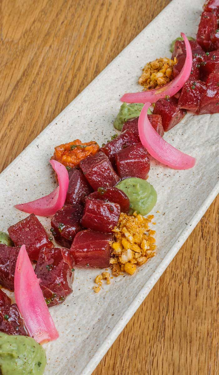 Dados de atún rojo marinados con guacamole, cebolla encurtida y maíz tostado servidos en restaurante Kulto en Madrid Retiro