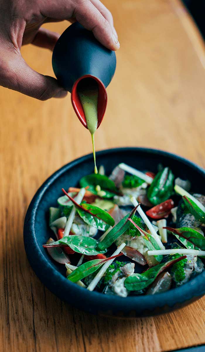 Primer plano de una salsa siendo vertida sobre un plato gourmet