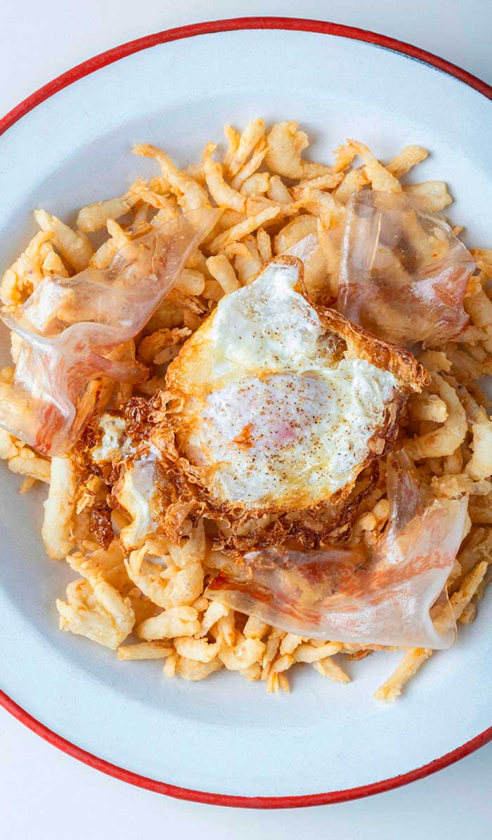 Plato de gamba cristal frita con huevo “cobarde” y papada ibérica ahumada servido en Kulto, restaurante en Madrid Retiro